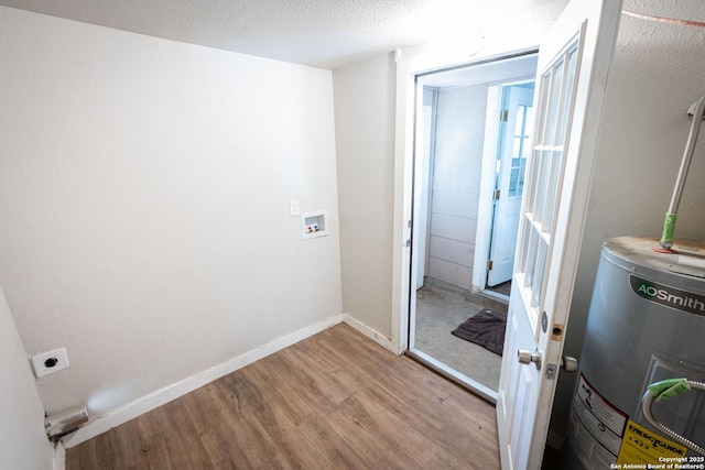 interior space featuring baseboards, washer hookup, water heater, wood finished floors, and laundry area