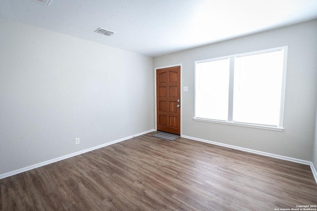 spare room featuring baseboards, wood finished floors, and visible vents