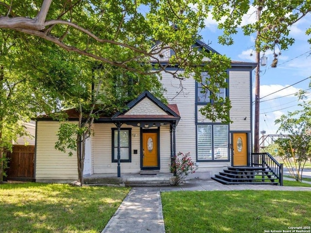 view of front of house featuring fence, a front lawn, and covered porch