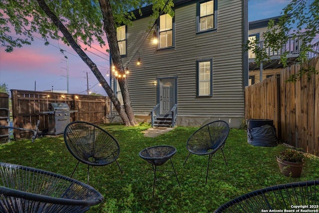 rear view of property with a fenced backyard, a yard, and entry steps