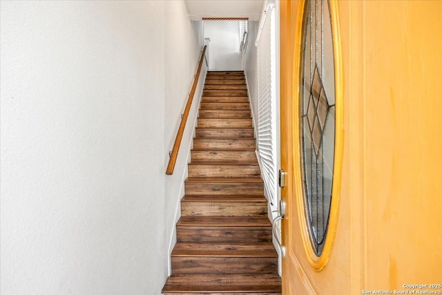 staircase featuring a textured wall and wood finished floors