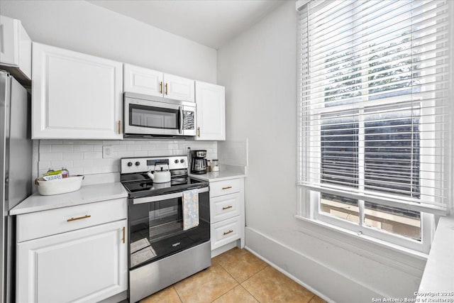 kitchen featuring light countertops, tasteful backsplash, stainless steel appliances, and light tile patterned floors