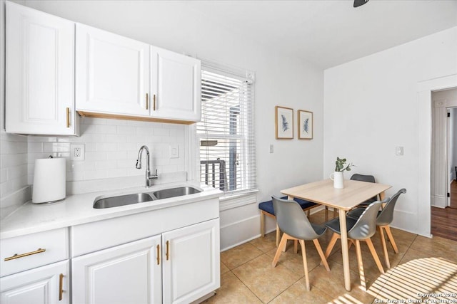 kitchen with light countertops, light tile patterned flooring, decorative backsplash, and a sink