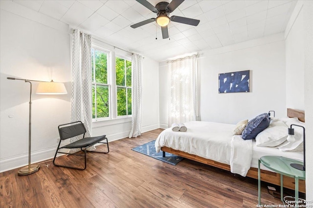 bedroom featuring ceiling fan, baseboards, and wood finished floors