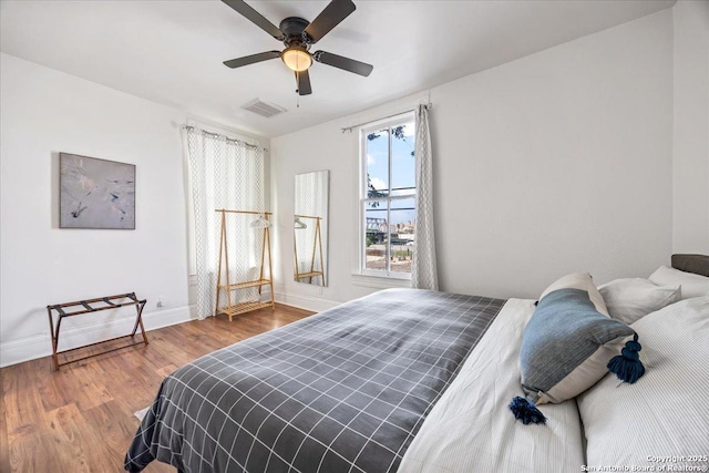 bedroom featuring ceiling fan, baseboards, wood finished floors, and visible vents