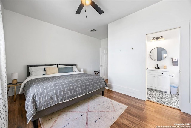 bedroom with light wood-style flooring, a sink, baseboards, visible vents, and connected bathroom