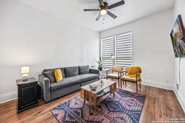 living area featuring baseboards, a ceiling fan, and wood finished floors