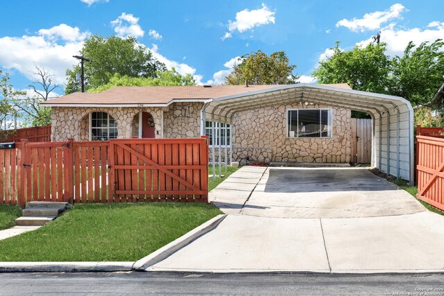 ranch-style house featuring a gate, concrete driveway, a carport, stone siding, and fence private yard