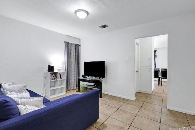 bedroom featuring a textured ceiling, visible vents, baseboards, and light tile patterned floors