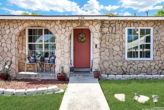 view of exterior entry featuring a porch and stone siding