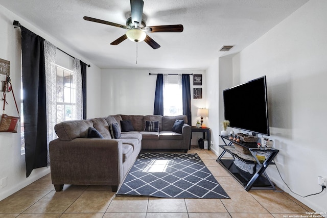 living room featuring ceiling fan, a textured ceiling, visible vents, and light tile patterned floors