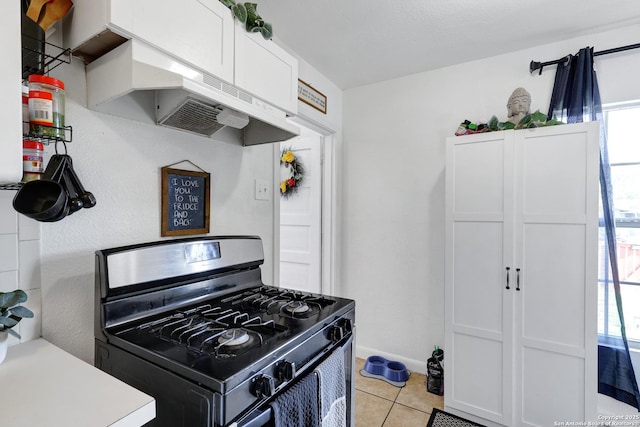 kitchen featuring white cabinets, light tile patterned flooring, gas range, light countertops, and under cabinet range hood