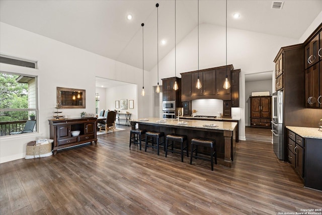 110 Madrone Trl, Boerne, TX 78006 - kitchen with visible vents, dark brown cabinetry, a breakfast bar, high vaulted ceiling, and appliances with stainless steel finishes