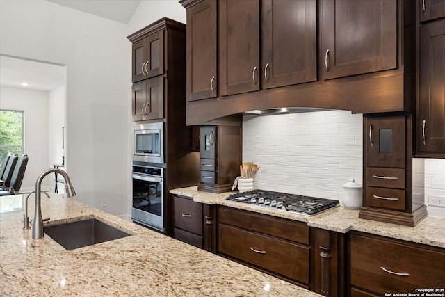 110 Madrone Trl, Boerne, TX 78006 - kitchen featuring stainless steel appliances, a sink, light stone countertops, dark brown cabinetry, and tasteful backsplash