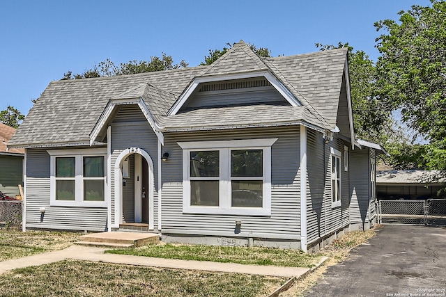 view of front of home featuring driveway, fence, and a shingled roof