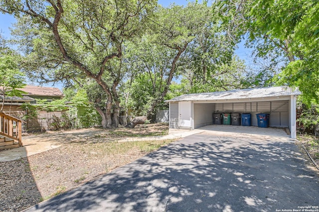 exterior space featuring driveway, a carport, and fence