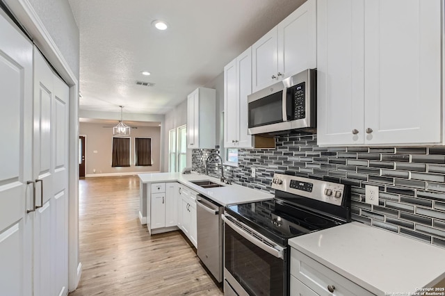 kitchen with light wood-type flooring, visible vents, stainless steel appliances, and a sink