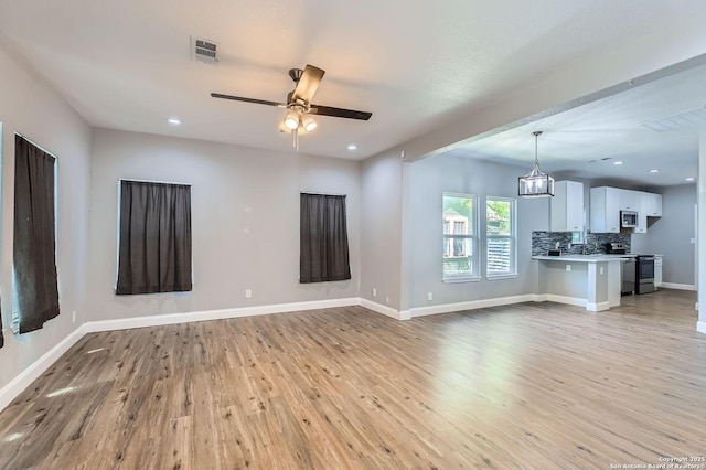 unfurnished living room featuring ceiling fan with notable chandelier, baseboards, recessed lighting, and light wood-style floors
