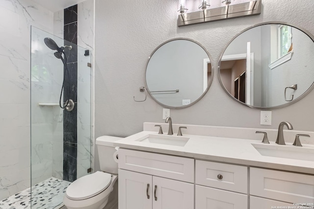 full bath featuring toilet, a sink, a marble finish shower, and double vanity