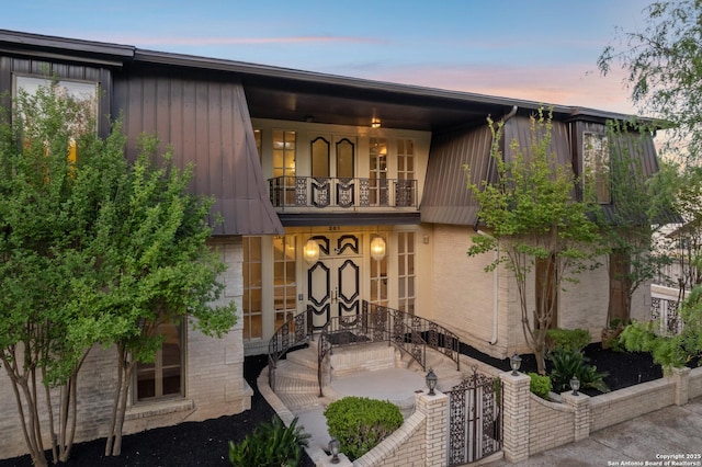 view of front of house featuring a balcony and brick siding