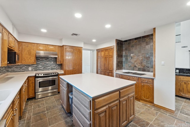kitchen with tasteful backsplash, visible vents, stone finish floor, under cabinet range hood, and appliances with stainless steel finishes