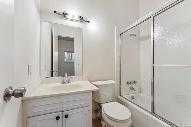 bathroom with combined bath / shower with glass door, toilet, and vanity