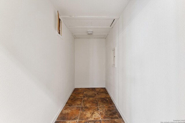corridor featuring stone finish flooring and baseboards