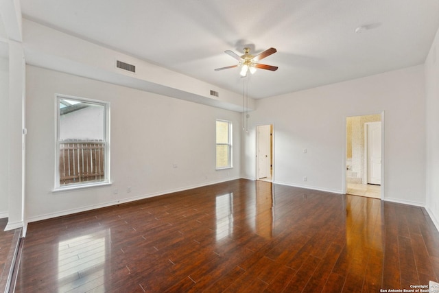 empty room featuring wood finished floors, visible vents, a ceiling fan, and baseboards