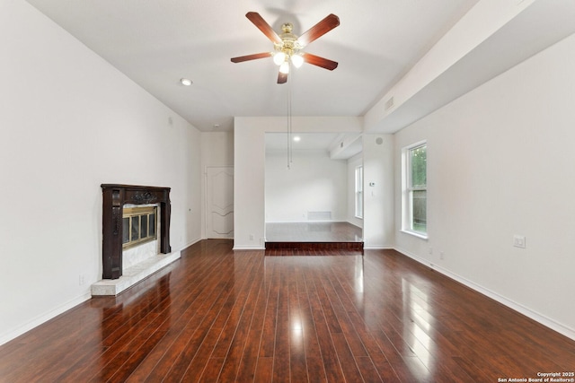 unfurnished living room with ceiling fan, a glass covered fireplace, wood finished floors, and visible vents