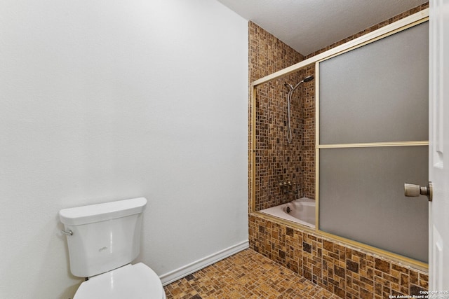 bathroom with tiled shower / bath combo, baseboards, and toilet