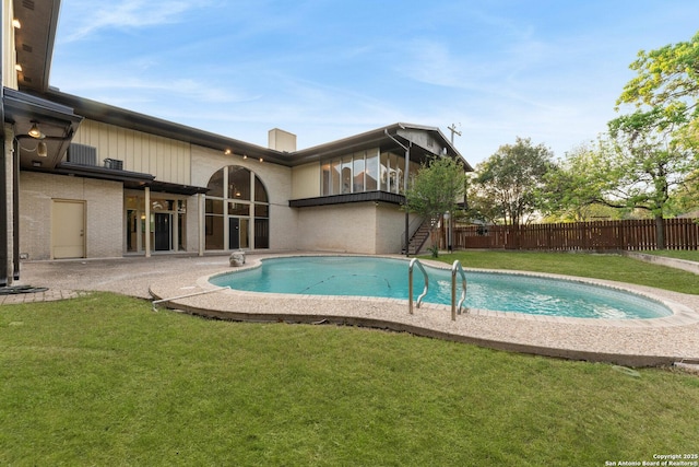 view of swimming pool featuring fence, a lawn, a fenced in pool, and stairway