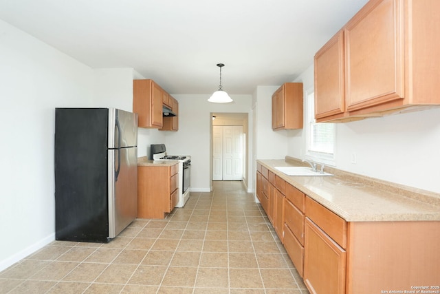 kitchen with under cabinet range hood, light countertops, a sink, white gas stove, and freestanding refrigerator