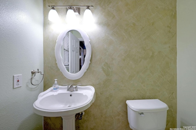 half bath featuring toilet and a sink