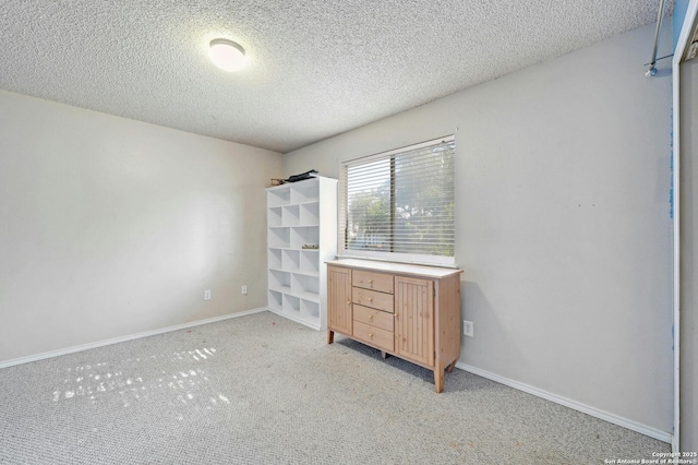 unfurnished bedroom featuring light colored carpet, baseboards, and a textured ceiling
