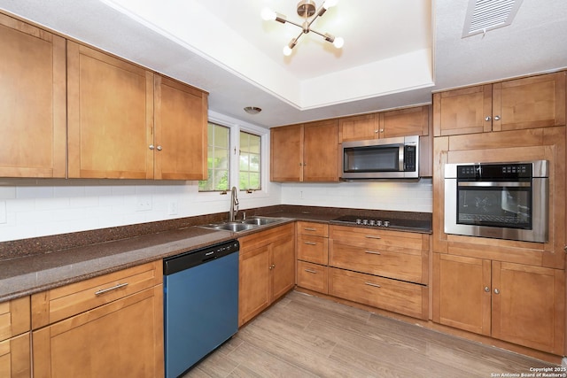 kitchen featuring stainless steel appliances, a sink, visible vents, backsplash, and a raised ceiling