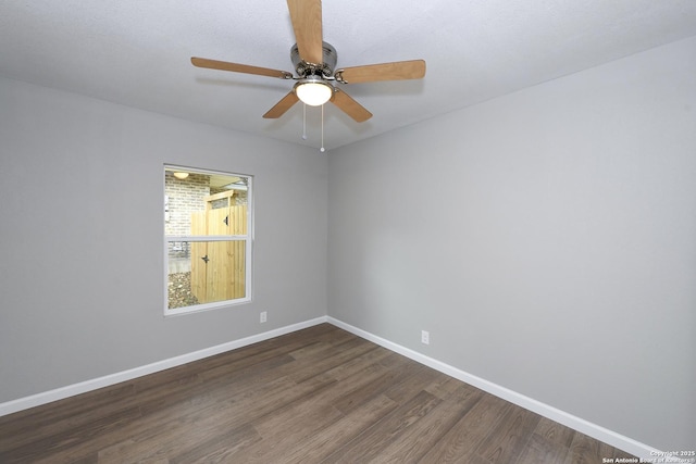 spare room featuring baseboards, ceiling fan, and dark wood-style flooring