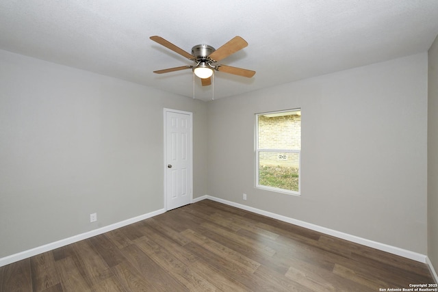 spare room featuring baseboards, a ceiling fan, and dark wood-style floors