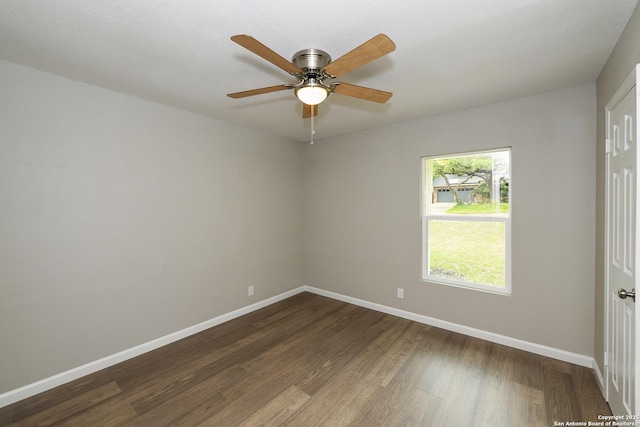 spare room featuring dark wood-type flooring, a ceiling fan, and baseboards