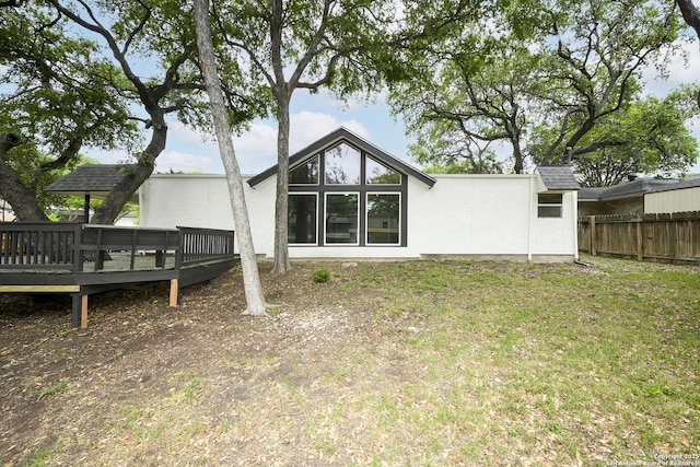 back of property featuring fence, a wooden deck, a yard, and stucco siding