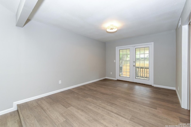 empty room featuring baseboards, french doors, and wood finished floors