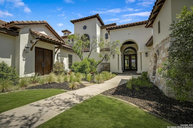 entrance to property with french doors, a tiled roof, and stucco siding