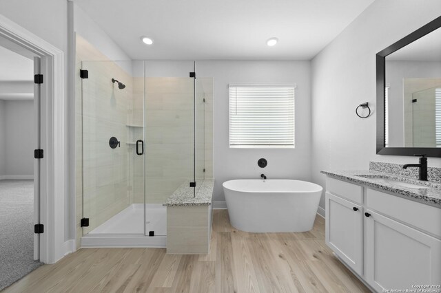 bathroom featuring a freestanding bath, a shower stall, vanity, and wood finished floors