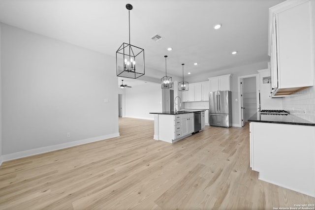 kitchen with a chandelier, freestanding refrigerator, dark countertops, and a sink