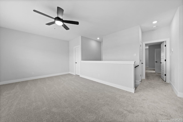 unfurnished room featuring light carpet, a ceiling fan, and baseboards