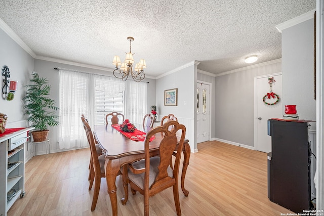 dining space with light wood-type flooring, a textured ceiling, ornamental molding, and an inviting chandelier