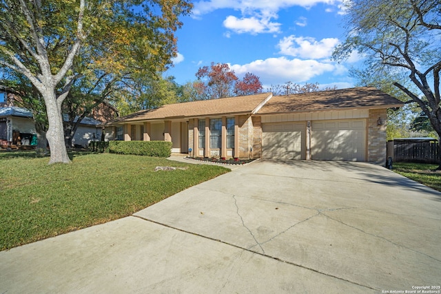 ranch-style home with concrete driveway, fence, brick siding, an attached garage, and a front yard