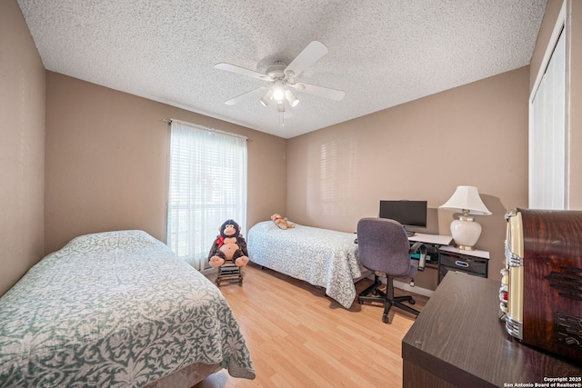 bedroom with ceiling fan, a textured ceiling, and light wood finished floors