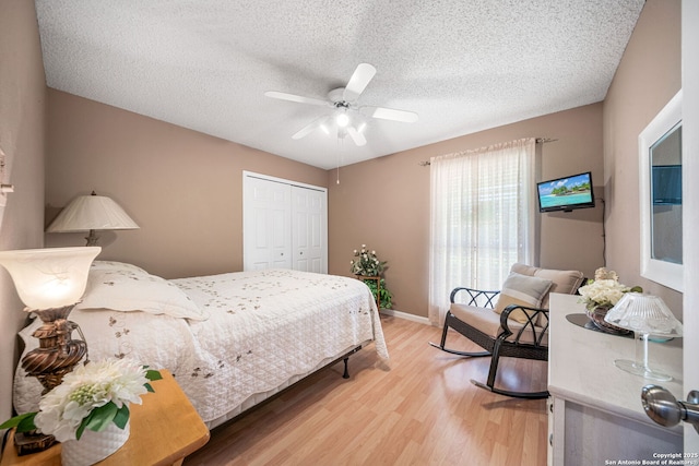 bedroom featuring a ceiling fan, light wood-style floors, a closet, baseboards, and a textured ceiling