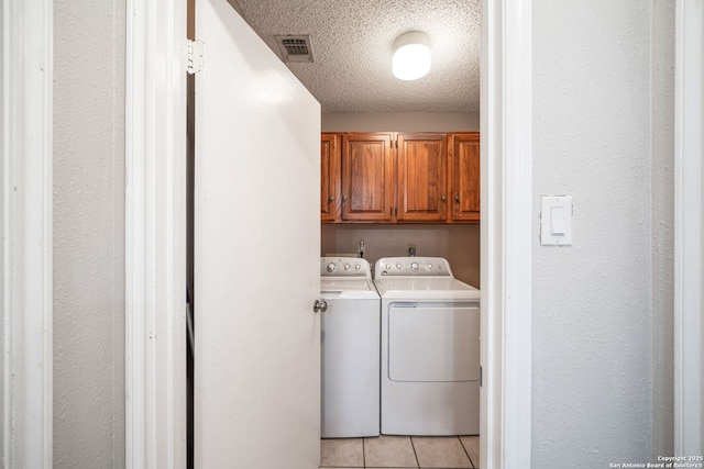 laundry area with washer and clothes dryer, a textured ceiling, light tile patterned floors, cabinet space, and visible vents