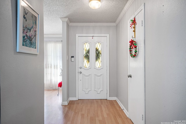 entrance foyer with baseboards, crown molding, a textured ceiling, and light wood-style flooring